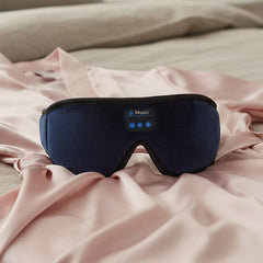 A dark blue velvet sleep mask with black trim and an integrated control panel labeled 'Music' on a white background.