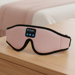 Pink sleep mask with Bluetooth control panel on a wood surface