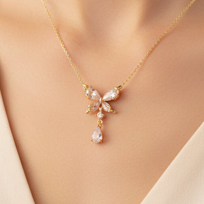 Gold necklace with a bow and teardrop pendant on a white background