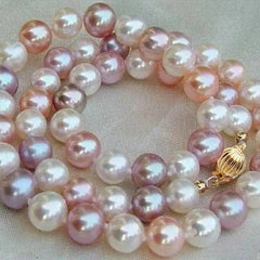 A freshwater pearl necklace in shades of pink, white, and lavender, arranged in a double-strand necklace with a gold clasp on a neutral beige fabric background.