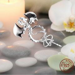 Back of a sterling silver dragon pearl cage on a bed of stone and orchids