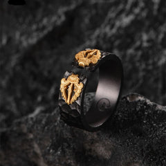 Black ring with gold designs on a textured dark background