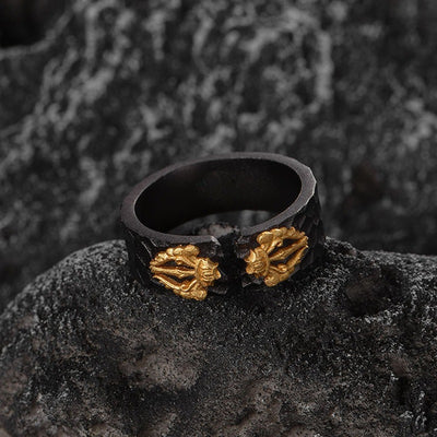 Black ring with gold leaf designs on a dark textured surface