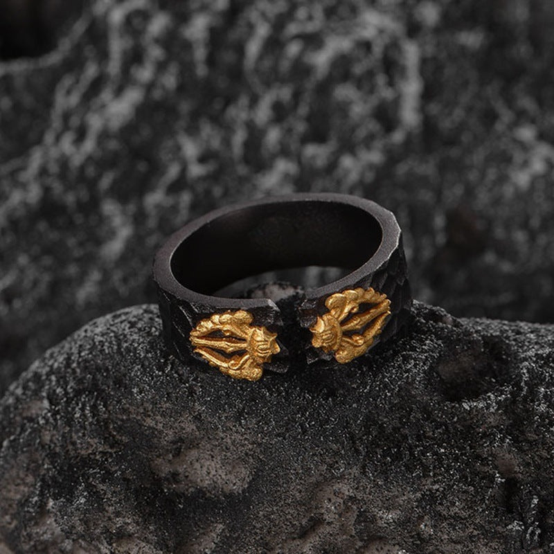 Black ring with gold leaf designs on a dark textured surface