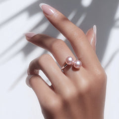 Hand wearing a double pearl sterling silver ring with two pink pearls on a white neutral background