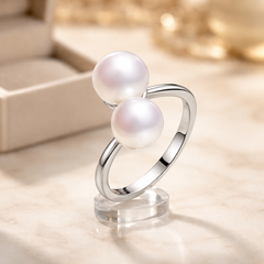 White double pearl sterling silver ring on a clear stand with a soft focus background
