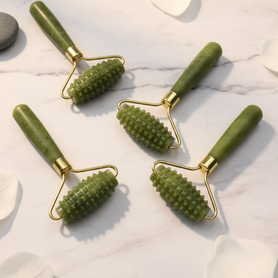 Four green skin care rollers with gold accents on a white background.