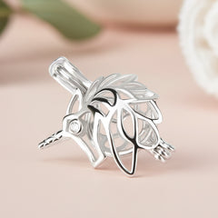 A sterling silver unicorn pearl cage with a small clear gemstone in one eye, shown on a soft tan background.