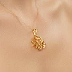 A gold lotus flower pendant charm with a polished finish, shown on a light-skin background.