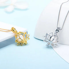Two lotus flower pendant necklaces shown on white display forms, one in polished yellow gold and one in polished silver, against a light blue background.