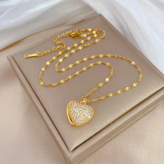 Gold heart-shaped necklace with clear stones on a beige box