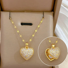 Gold heart-shaped necklace with embedded stones on a beige jewelry box