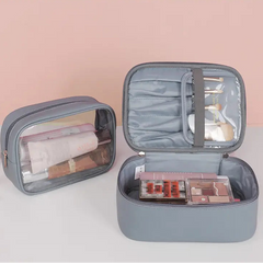 Gray cosmetic bag with makeup items on a light pink background