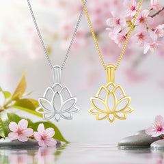 Two lotus flower pendant necklaces on silver chains, one in polished silver and one in polished yellow gold, displayed side-by-side in front of cherry blossoms
