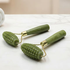 Two green skin care rollers with textured wheels on a white background with green leaves.