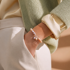 Pastel freshwater pearl bracelet with lavender, peach, and cream pearls worn on the wrist, styled with a light green knit sweater and cream satin blouse, photographed in soft natural light for a refined boutique look.