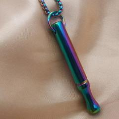 Multicolored metal whistle on a chain against a beige fabric background