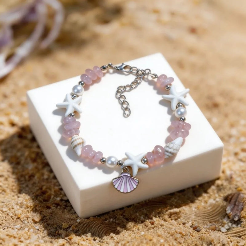 Bracelet with starfish and shell charms on a sand-like surface