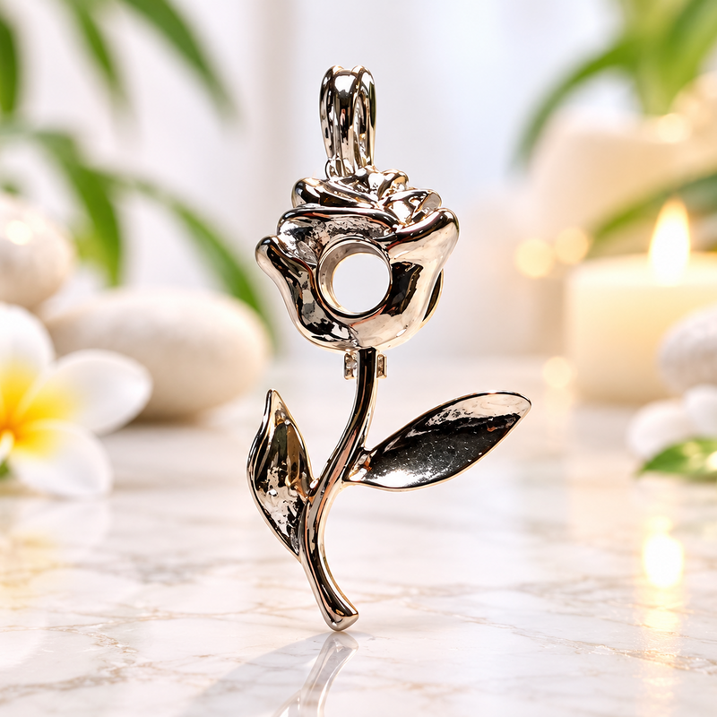 A close-up of a silver-toned metal rose-shaped charm or pendant on a white background with green leaves and white flower petals scattered about