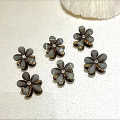 Set of six flower-shaped earrings on a textured surface