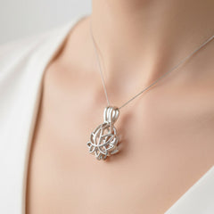 A polished silver lotus‑shaped pendant hanging from a delicate chain, worn around the neck of a person in a white V‑neck top. The open‑petal lotus design is centered and clearly visible, highlighting the pendant’s elegant craftsmanship.