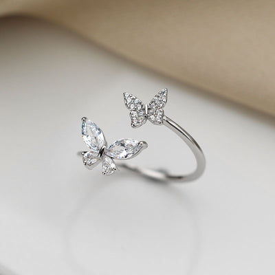 Silver butterfly-shaped ring on a soft beige background