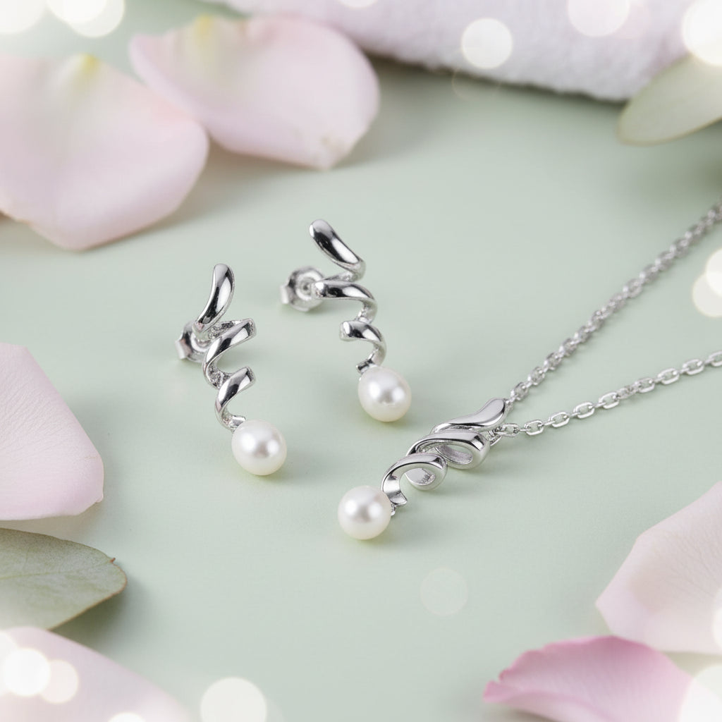 Silver jewelry set featuring a necklace and matching earrings with curved silver filigree details and round white freshwater pearls, displayed on a dark textured background.