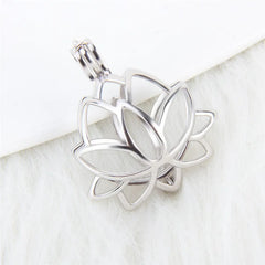 A silver-toned lotus flower pendant with an openwork design and a bail at the top, photographed on a soft white textured surface with a white background.