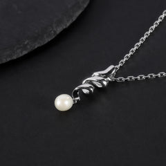Silver necklace with a pearl pendant on a dark surface