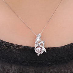 A silver pendant necklace featuring a mermaid design with a pearl, shown worn on a model's neck over a black top.