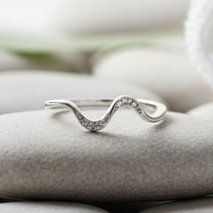 Silver wave-shaped ring on a textured stone surface