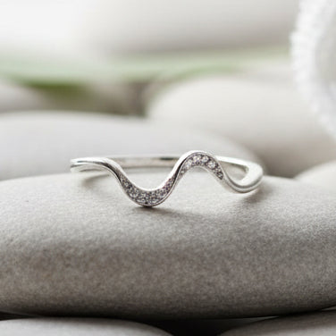 Silver wave-shaped ring on a textured stone surface