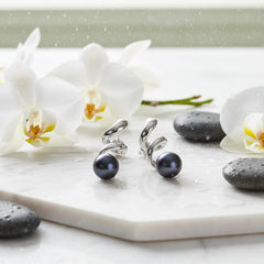 black sterling silver pearl earrings on a marbel counter with orchids