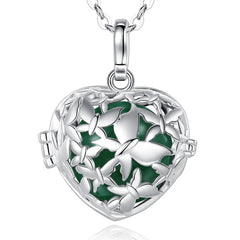 A silver heart-shaped locket pendant necklace with a butterfly cutout design and a dark green enamel background, shown on a white background with a faint reflection below.