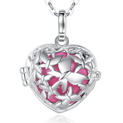 A silver heart-shaped locket pendant necklace with a butterfly design and a vibrant pink enamel background, shown on a white background with a subtle reflection.