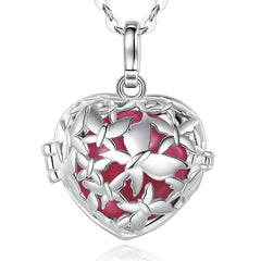 A silver heart-shaped locket pendant necklace with a butterfly design and a vibrant redish pink enamel background, shown on a white background with a subtle reflection.