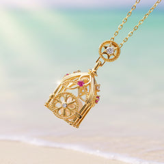 Sterling silver gold-toned premium-filigree-lantern-pearl-cage-necklace on a soft tan and aqua background