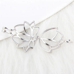 A sterling silver-toned metal flower-shaped pearl cage displayed open on a white textured surface.