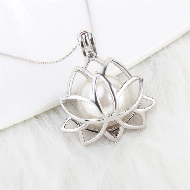 A silver lotus flower pendant necklace with a white pearl in the center, resting on a white textured surface.