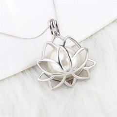 A silver lotus flower pendant necklace with a white pearl in the center, resting on a white textured surface.