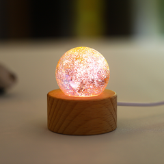 A multicolor orange‑pink orb with soft gradient lighting, displayed on a wooden LED stand.