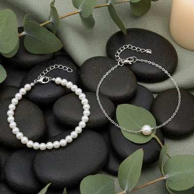 Two pearl bracelets on black stones with greenry background