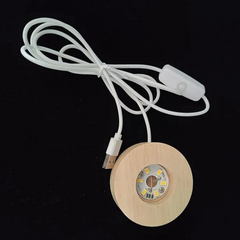 A circular wooden LED base with a USB cable attached, designed to illuminate glass orbs.