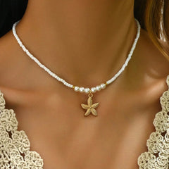 Pearl necklace with a gold starfish pendant on a model wearing a lace top.