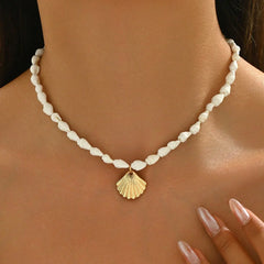 Pearl necklace with a gold shell pendant on a person's neck