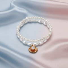 Pearl bracelet with a gold shell charm on a white background