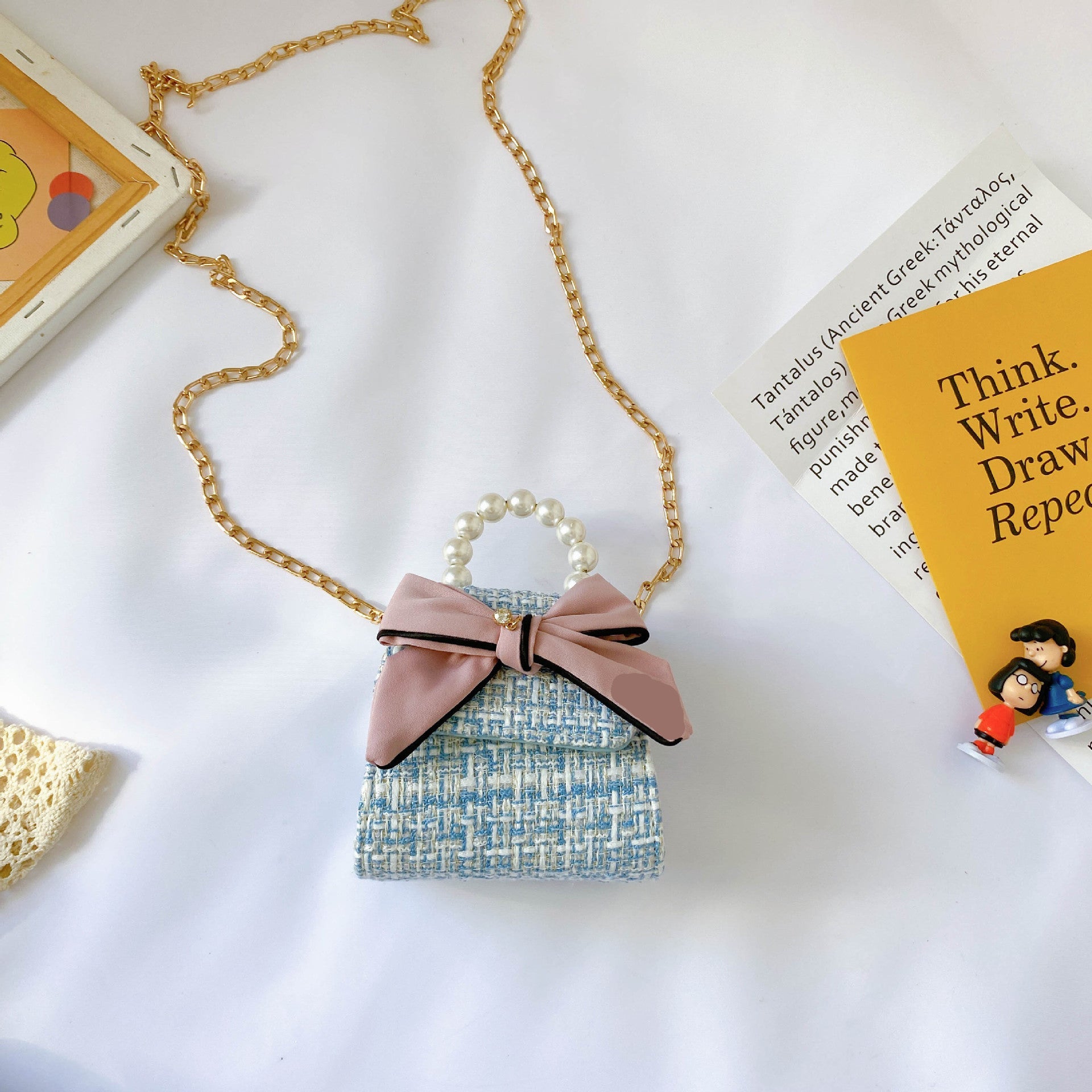 Small decorative bag with a pink bow and 'love' text on a white surface with a book in the background.