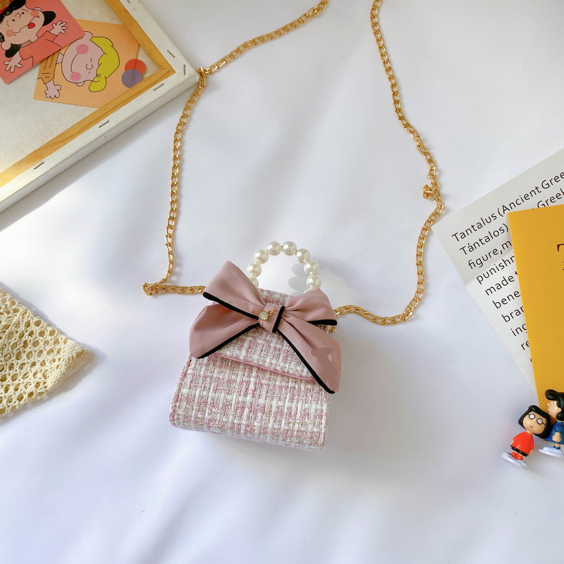 Small pink handbag with a bow and gold chain on a white surface