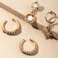 Gold hoop earrings with gemstone accents on a beige surface