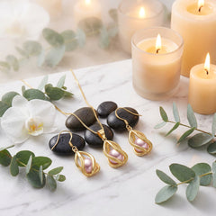 Gold jewelry set with purple pearls on a white background with greenery